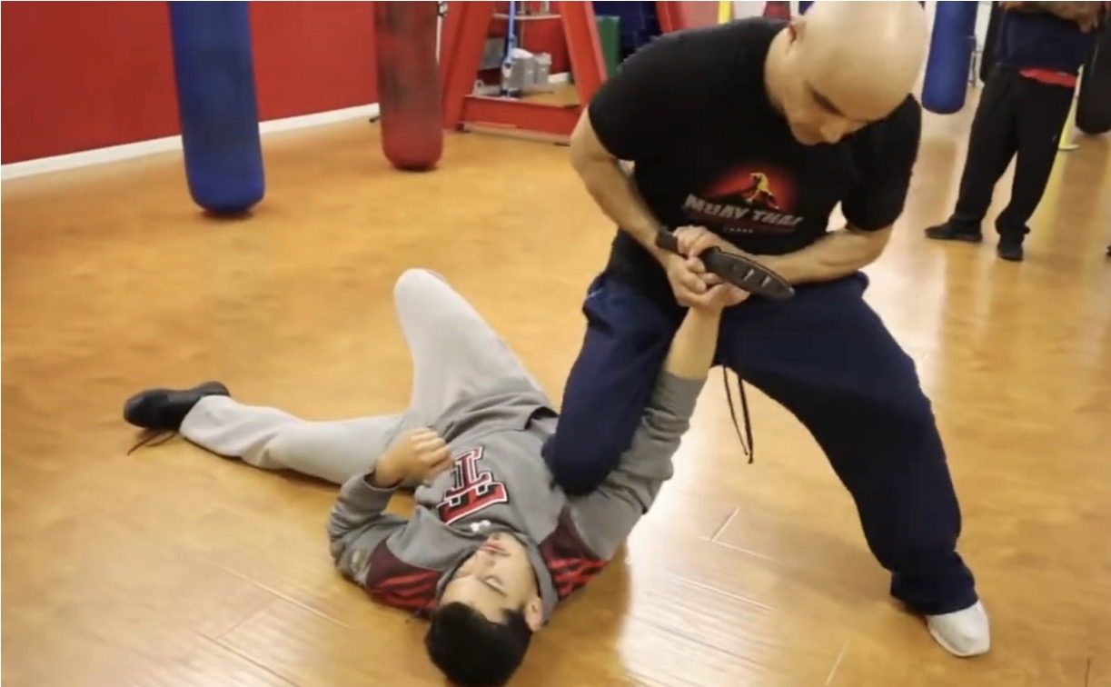 Master Edward controlling a training partner on the ground and securing a training knife