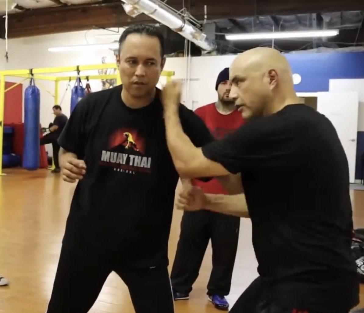 Master Edward Garcia checking a training partner's arm at close range during empty-hand training